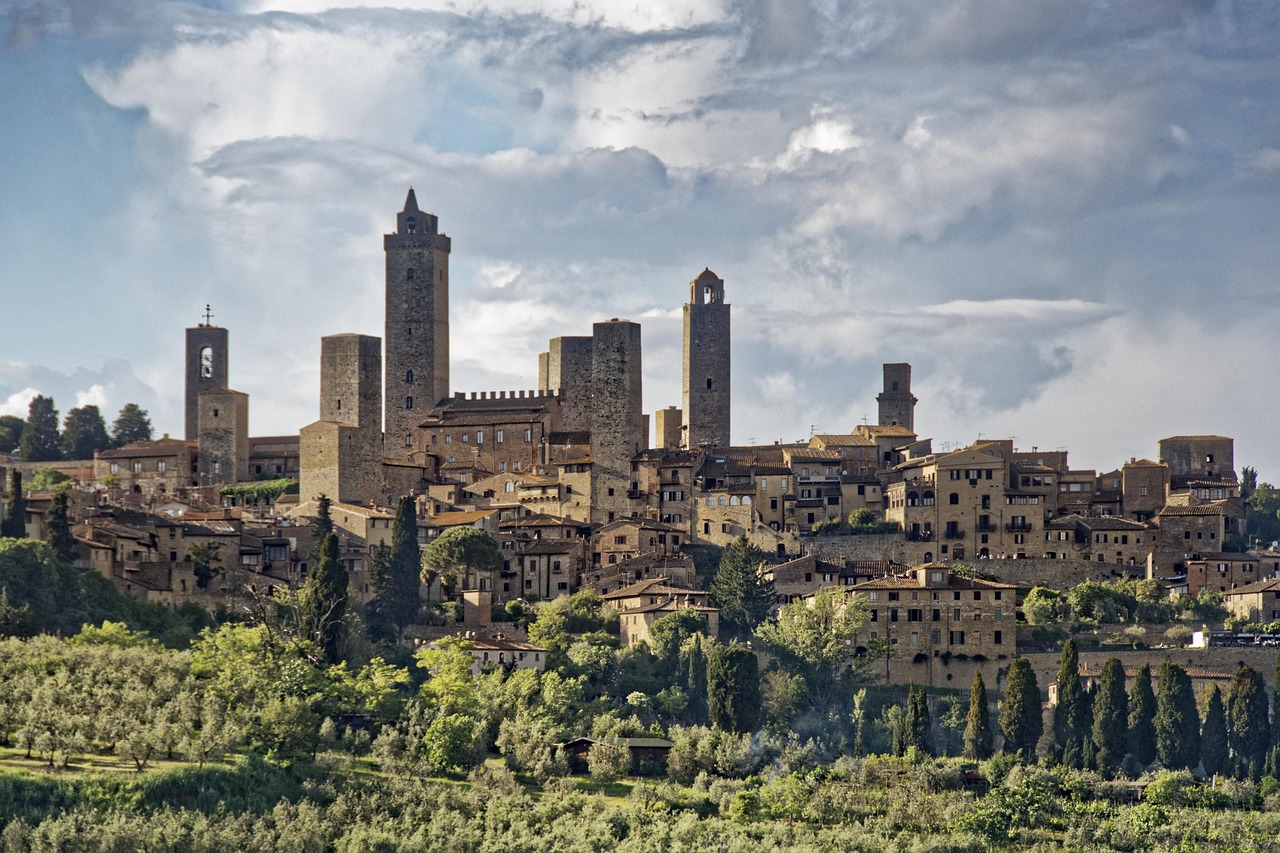Panorama del borgo di San Gimignano con torri medievali e vigneti circostanti.