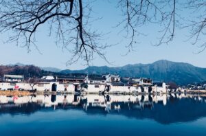 Panorama del lago con il paese che si riflette sull'acqua cristallina al tramonto.