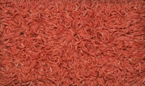 Carne macinata in vaschetta con fondo grigio, evidenziando il rischio per la freschezza e la qualità.