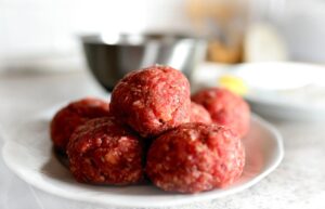 Polpette pronte per la cottura, adagiate su un piatto, dopo il riposo in frigo per una consistenza perfetta.