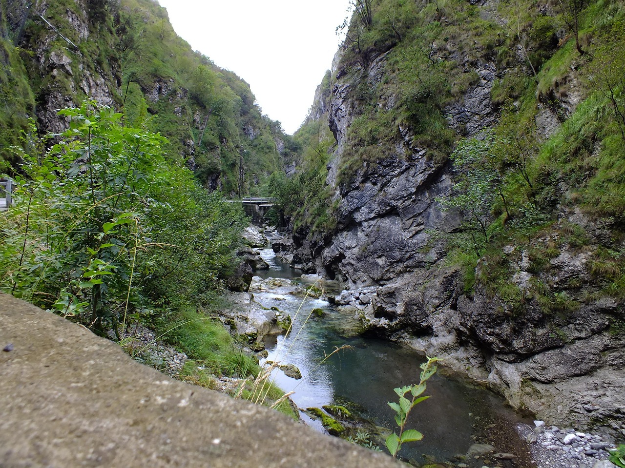Escursionista che attraversa un sentiero panoramico nel Grand Canyon del Veneto, circondato da rocce e vegetazione.