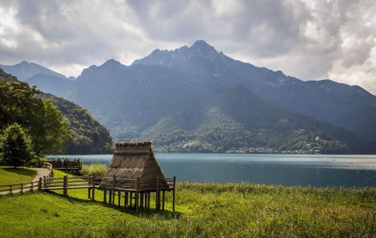 Panorama del lago di Tenno con il borgo medievale sullo sfondo, circondato da natura e montagne.