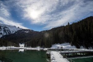 Lago di Braies al tramonto, con riflessi colorati sull'acqua e natura serena circostante.
