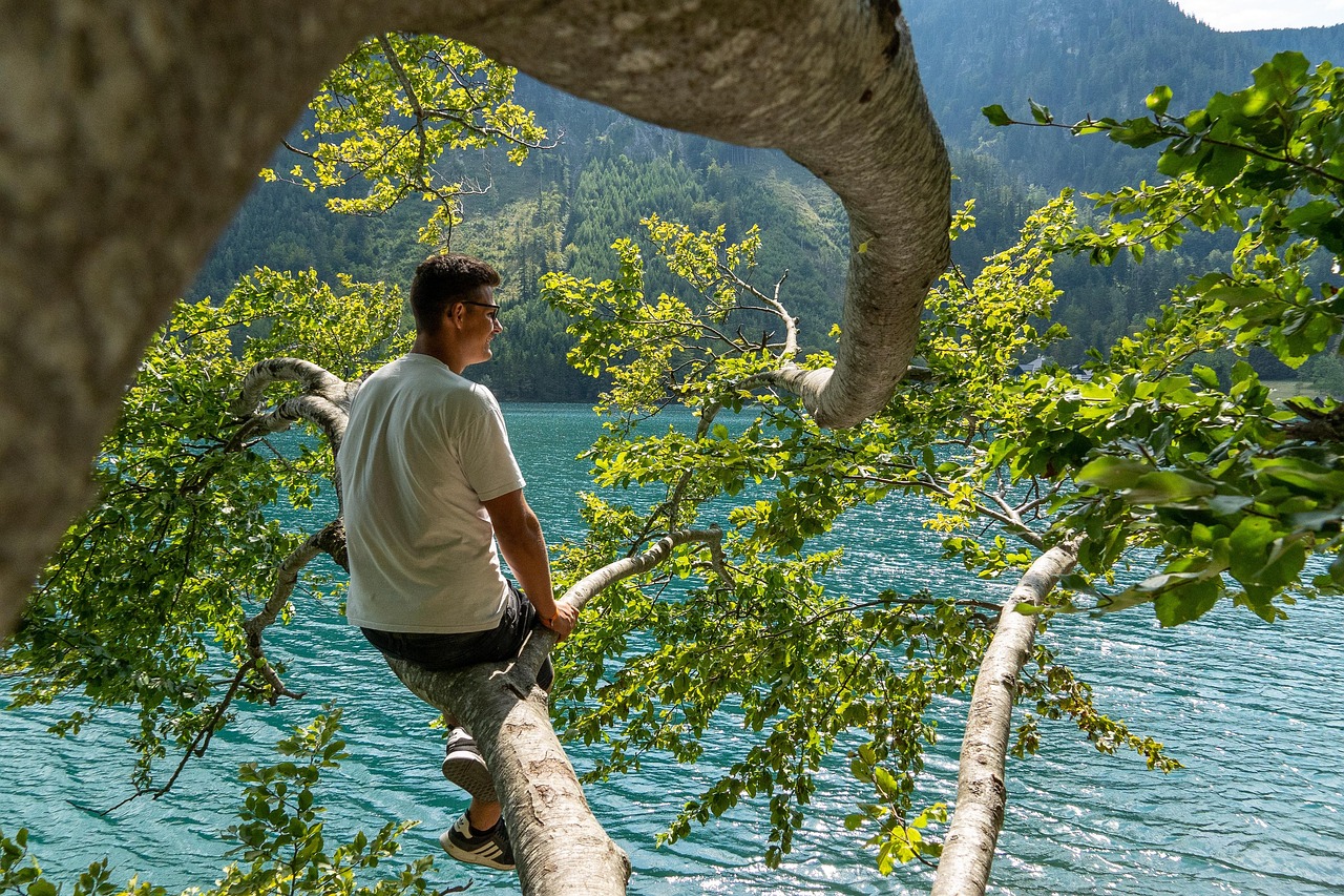 Vista panoramica del lago di Molveno circondato da montagne, con attività di sport acquatici in corso.