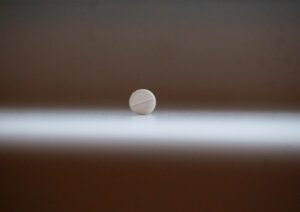 Immagine di un flacone di melatonina su un tavolo con un orologio in background, simboleggiando il ritmo circadiano.